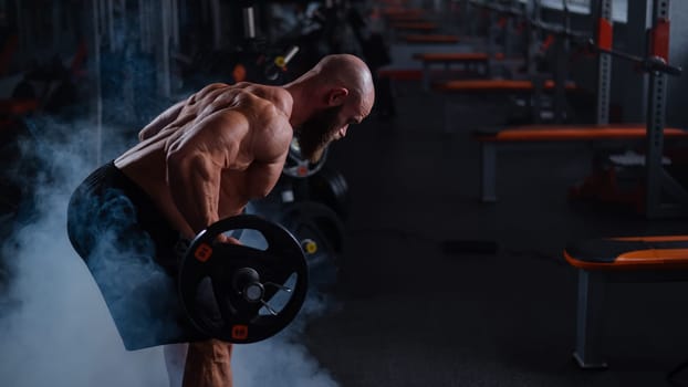 Caucasian bald topless man doing an exercise with a barbell in the gym