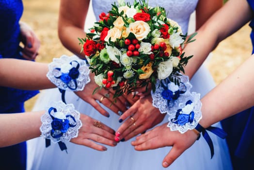 hands bridesmaids with bracelets and bride with a bouquet together
