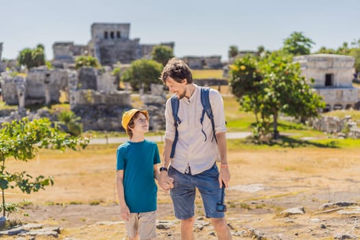 Father and son tourists enjoying the view Pre-Columbian Mayan walled city of Tulum, Quintana Roo, Mexico, North America, Tulum, Mexico. El Castillo - castle the Mayan city of Tulum main temple.