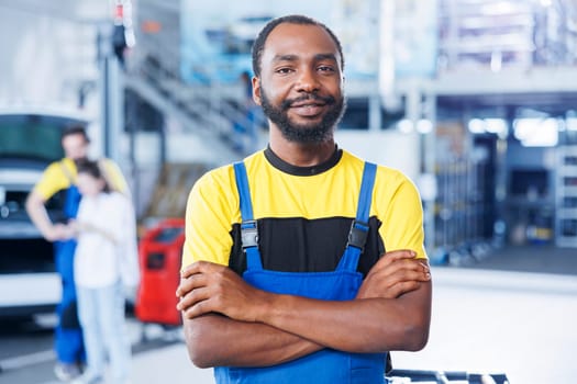 Portrait of smiling BIPOC mechanic in auto repair shop tasked with changing cars brake fluid. Certified employee in garage ready to start doing checkups on vehicles in garage workspace