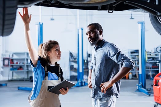 African american client shocked by price after repairman in car service uses tablet to calculate repair invoice. Garage specialist surprising BIPOC man with final costs after servicing his vehicle