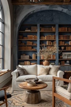 A living room with a large blue bookcase and a white couch. The couch is covered in pillows and there is a vase with flowers on the coffee table. The room has a cozy and inviting atmosphere