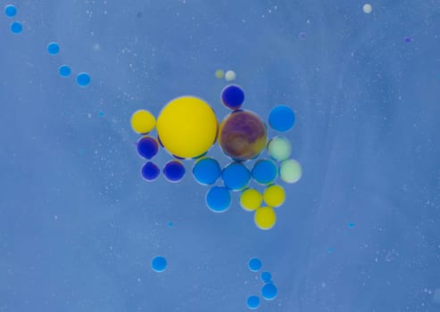 A myriad of oil droplets intermingling with water, creating a mesmerizing effect reminiscent of a galaxy.