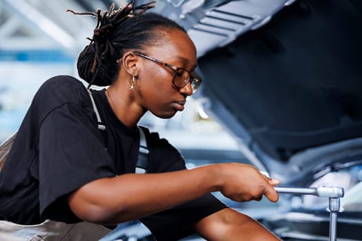 Repair shop technician examines damaged car motor using advanced mechanical tools, ensuring peak automotive performance. Proactive worker in garage workplace conducts routine vehicle checkup