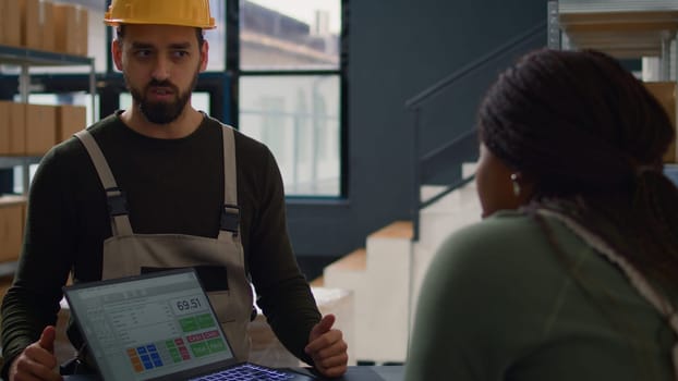 Fulfillment center employee carrying out the logistics of receiving, processing, storing and sending inventory according to purchase orders and shipping schedules, helped by knowledgeable colleague