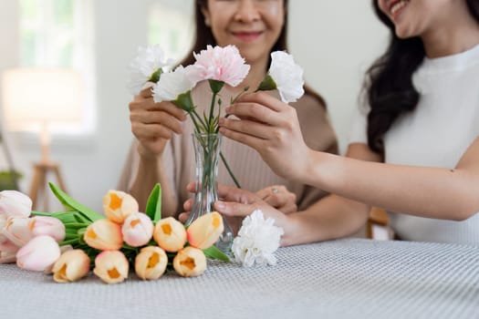 Mother and daughter arrange flower together at home on the weekend, family activities, mother and daughter do activities together on Mother's Day.