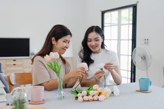 Mother and daughter arrange flower together at home on the weekend, family activities, mother and daughter do activities together on Mother's Day.