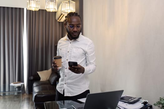 African American business man working with document and laptop while talking on mobile at home on couch. work from home concept.