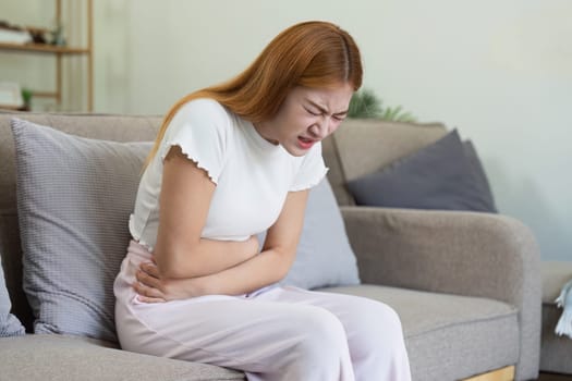 asian woman suffering from stomach ache, undergoing belly pain and discomfort, suffer from menstruation.