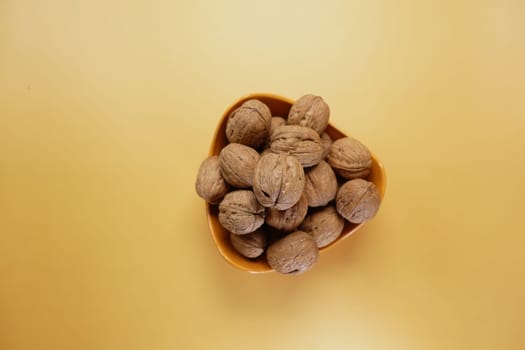 stack of natural walnuts in a bowl on orange color background ,