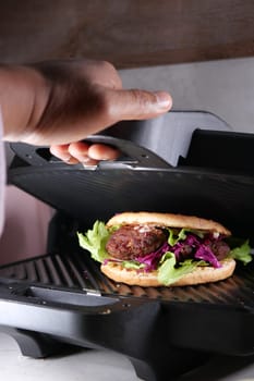 Sandwich with meatballs, lettuce, and red cabbage grilling.