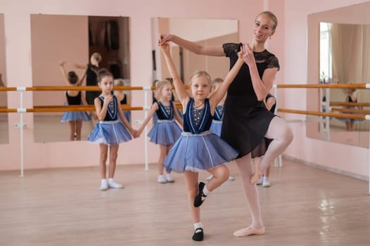 Children's ballet school. Caucasian woman teaching ballet to little girls