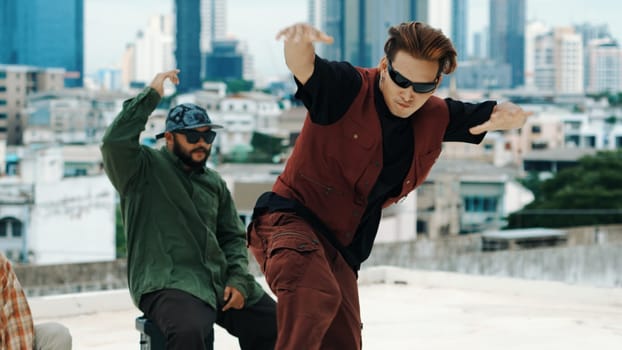 Motion shot of B-boy dance performance by professional street dancer at rooftop with sky scrapper, city view. Attractive asian hipster show energetic footstep. Outdoor sport 2024. Closeup. Endeavor.