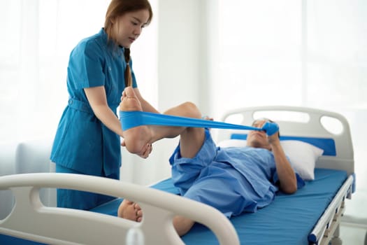 a woman in a blue uniform helps a man in a hospital bed.