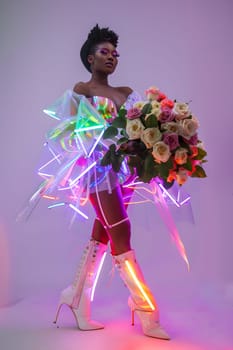 A woman in a purple dress and magenta boots is holding a bouquet of pink flowers. She looks like she is ready to perform on stage at a dance event
