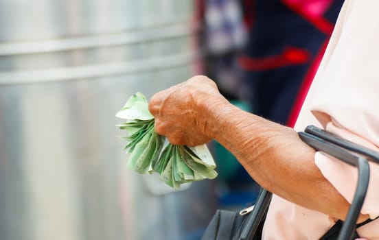 Close up of an elderly woman's hands holding money