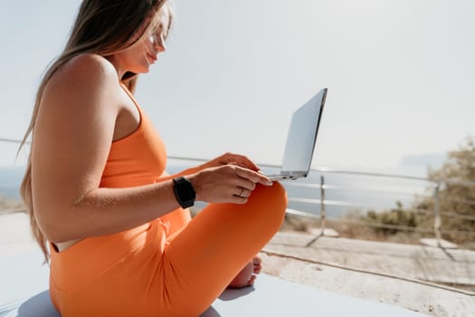 Digital nomad, Business woman working on laptop by the sea. Pretty lady typing on computer by the sea at sunset, makes a business transaction online from a distance. Freelance, remote work on vacation