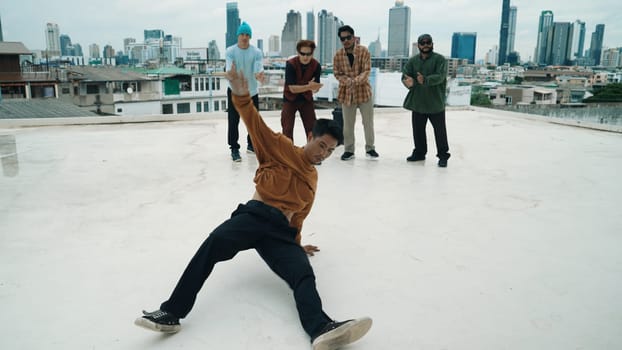 Professional break dance team practice B-boy dance while multicultural friends at rooftop. Young modern dancing group doing hip hop movement. Style,fashion,action. Outdoor sport 2024. Endeavor.