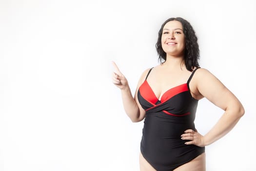 Portrait of attractive dreamy thick woman in red black swimsuit posing on white background. Body positive, photoshoot, selfie. Funny plus size model