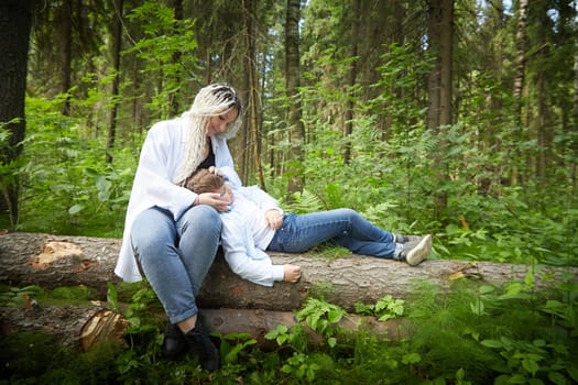 Funny mother with dreadlocks and fat boy happy walking in the forest on a sunny summer day