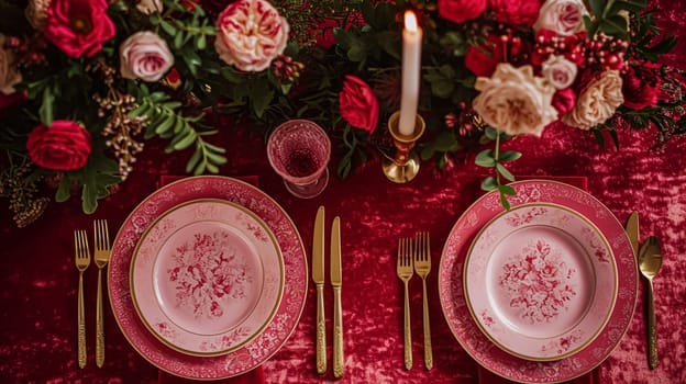 Festive table setting with cutlery, candles and beautiful red flowers in a vase.