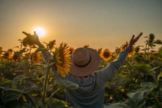 A woman in a straw hat is holding a sunflower. Concept of warmth and happiness, as the woman is surrounded by the bright and cheerful flower