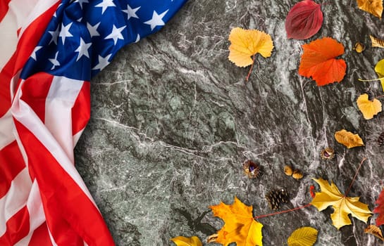 USA flag buried in yellow dry leaves. Autumn texture.