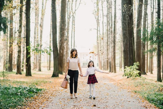 happy mother and daughter walking in the Park in autumn