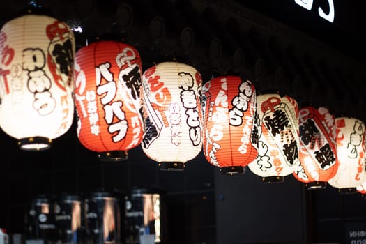 The restaurant is adorned with a row of colorful lanterns hanging from the ceiling, creating a vibrant atmosphere in the room