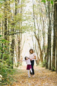 happy mom and daughter fall in the Park playing and laughing
