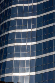 A modern skyscraper with a sleek facade stands tall against the backdrop of a clear blue sky, showcasing urban design and commercial real estate prowess