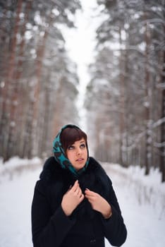 Russian girl in coat and scarf in cold winter in the woods