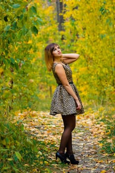 girl in dress and heels posing in autumn in the woods