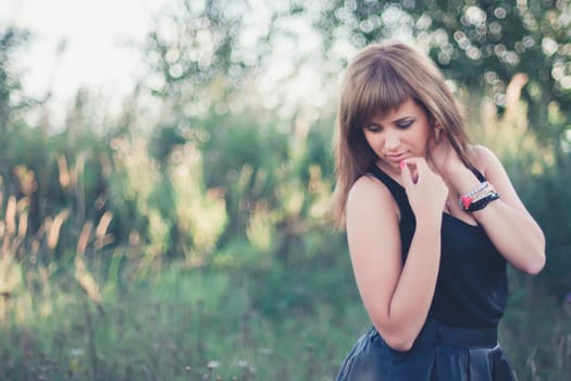 young Caucasian girl posing in summer at sunset in the field