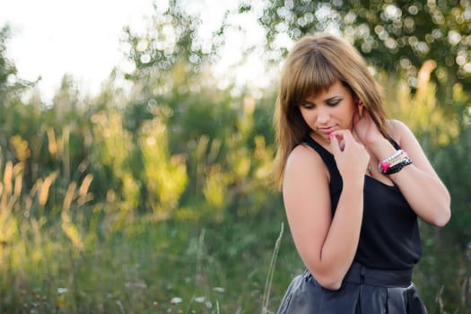 young Caucasian girl posing in summer at sunset in the field