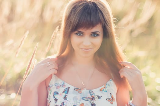 young Caucasian girl posing in summer at sunset in the field