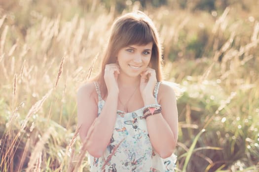 young Caucasian girl posing in summer at sunset in the field