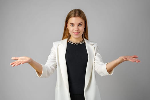 Young Woman Expressing Confusion With Hands Raised Against a Grey Background in studio