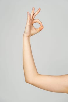 Young Woman Arm with Gesture close up on gray background