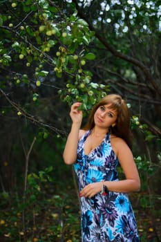 young Caucasian girl in blue dress posing in forest outdoors in summer