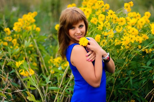 girl in the blue dress against the yellow blooming flowers
