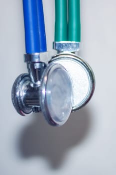 A closeup image showcasing a stethoscope with vibrant green and blue handles, resembling automotive lighting and plumbing valve designs