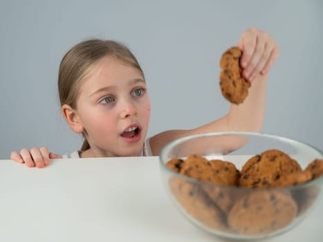 Little girl steals cookies from the table