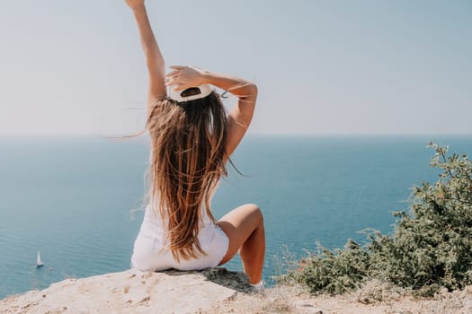 Woman travel sea. Young Happy woman in a long red dress posing on a beach near the sea on background of volcanic rocks, like in Iceland, sharing travel adventure journey