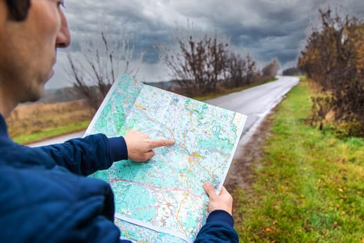 A man looks at a map on the road. Selective focus. People.