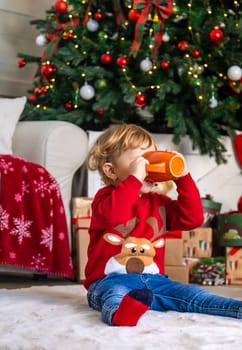 Children drink tea near the Christmas tree. Selective focus. Kid.