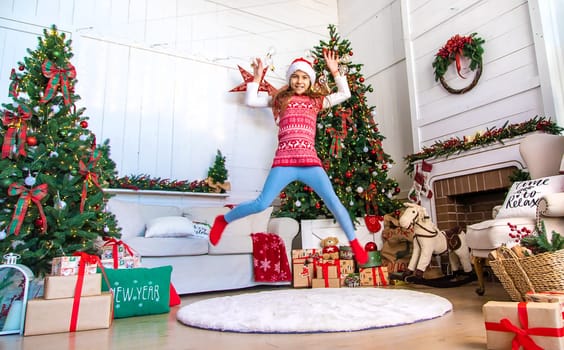 A child dances near a Christmas tree with a garland. Selective focus. Kid.