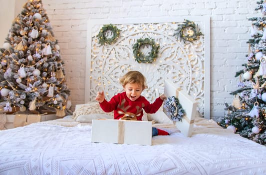 Child open Christmas gifts under the tree. Selective focus. Kid.