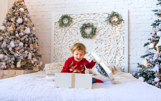 Child open Christmas gifts under the tree. Selective focus. Kid.