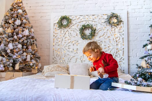 Child open Christmas gifts under the tree. Selective focus. Kid.